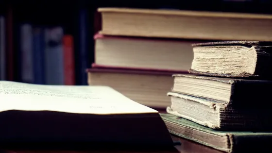 A stack of old hardcover books beside an open book